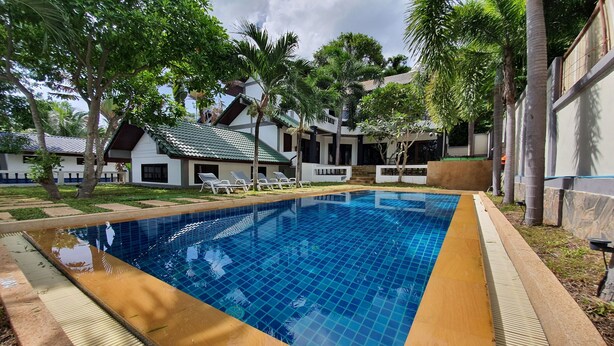 A rectangular swimming pool with blue tiles, surrounded by a wooden deck and palm trees. - NB Villa Celina (Koh Samui)