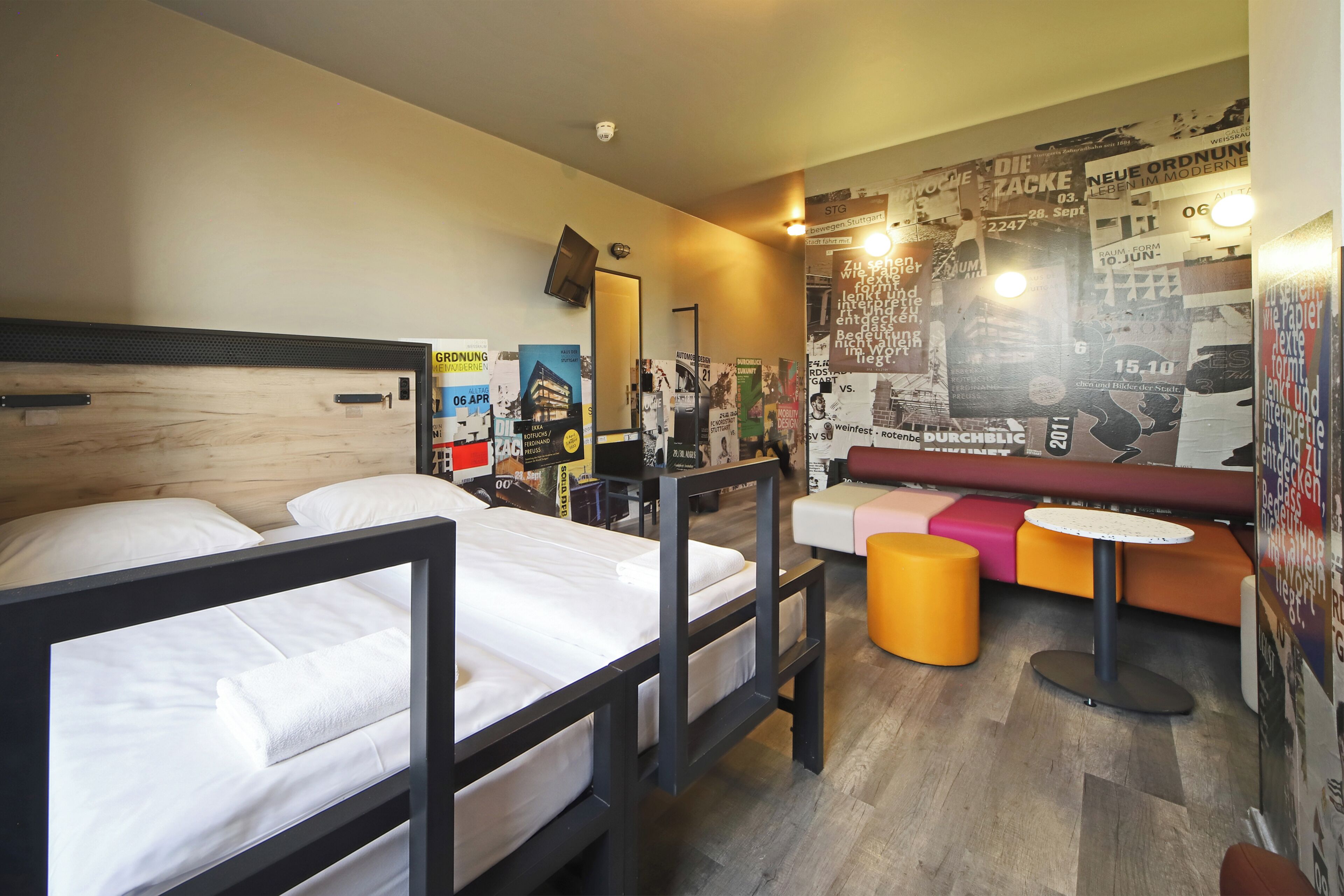 A hotel room with a bed, a desk, a chair, and a small table.