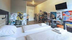 A hotel room with two beds, a flat-screen TV, and various posters on the walls. - a&o Stuttgart City - Hostel (Stuttgart)
