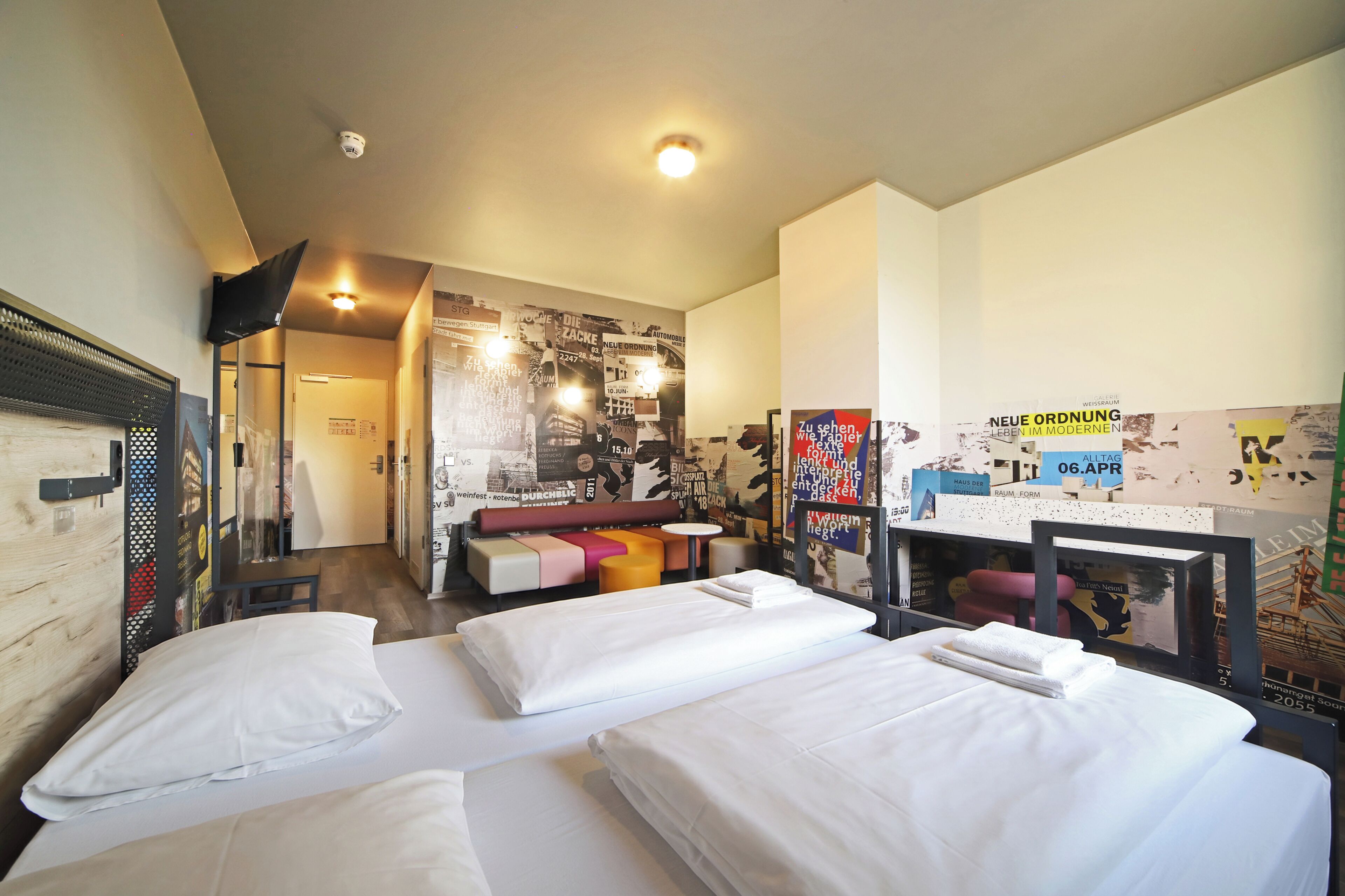 Habitación de hotel con dos camas, un escritorio y una zona de estar.