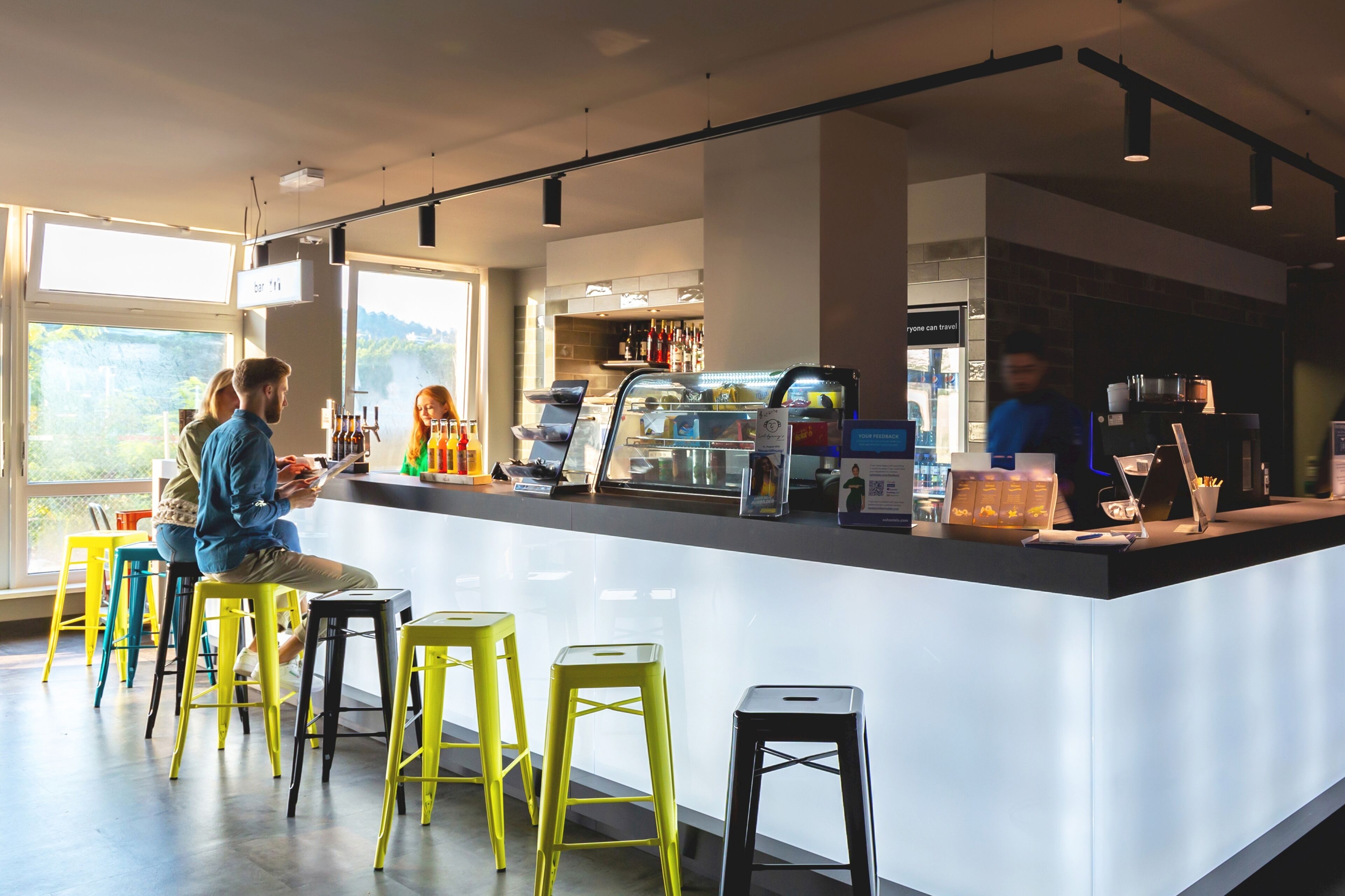 A modern bar area with a counter, stools, and a view of the outdoors.