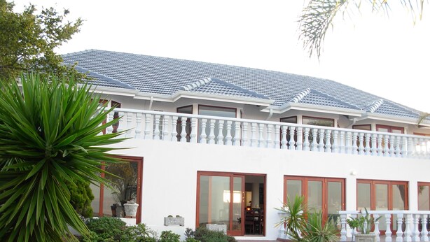 A two-story building with a white exterior, large windows, and a balcony with a white balustrade. - Magaliqua Guest House (Krugersdorp)
