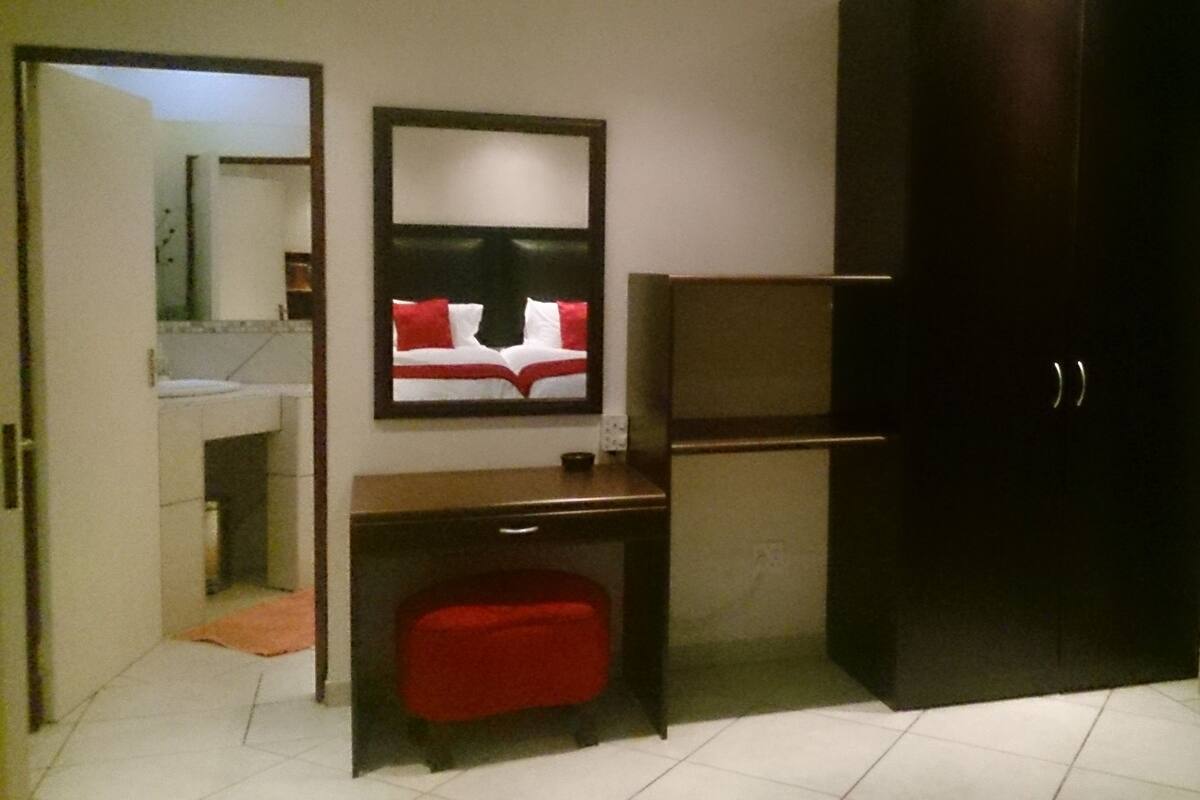 A hotel room with a bed, a desk, a chair, and a wardrobe.