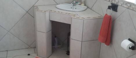 A bathroom with a sink, towel rack, and toilet paper holder.