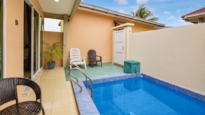 A swimming pool with a tiled deck, a chair, a potted plant, and a door. - Collection O Langkawi Near Pantai Cenang formerly Tokman Inn (Langkawi)