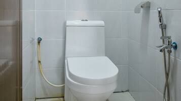 Een badkamer met toilet, douche en een glazen deur.