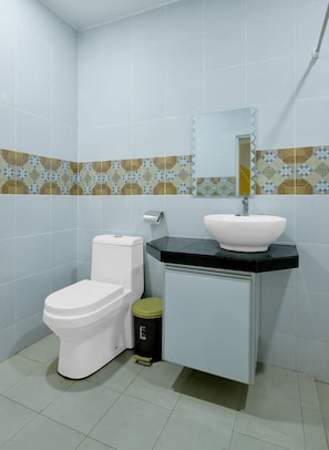 A bathroom with a toilet, sink, and trash bin.