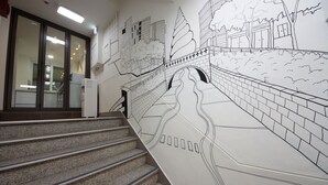 A staircase with a detailed mural on the wall depicting a cityscape. - K-Guesthouse Myeongdong 1 (Seoul)
