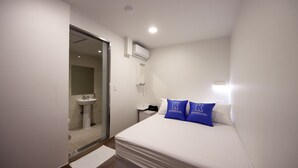 A hotel room with a bed, a bedside table, a mirror, and a bathroom visible through an open door. - K-Guesthouse Myeongdong 1 (Seoul)
