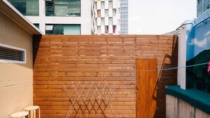 A wooden deck with a drying rack, two stools, and a metal bucket. - K-Guesthouse Myeongdong 1 (Seoul)