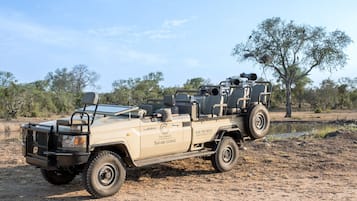 Vehículo tipo lodge de safari con plataforma, equipado con portaequipajes y neumático de repuesto.