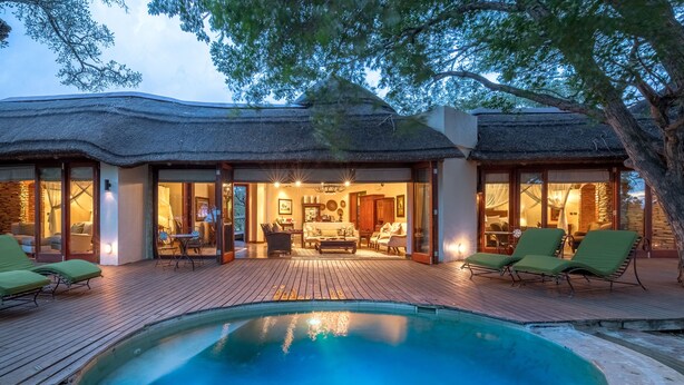 Un resort con piscina, asientos al aire libre y un edificio de techo de paja.