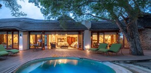 Un resort con piscina, asientos al aire libre y un edificio de techo de paja.