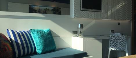 Una habitación de hotel moderna con una cama, un escritorio y un televisor montado en la pared.