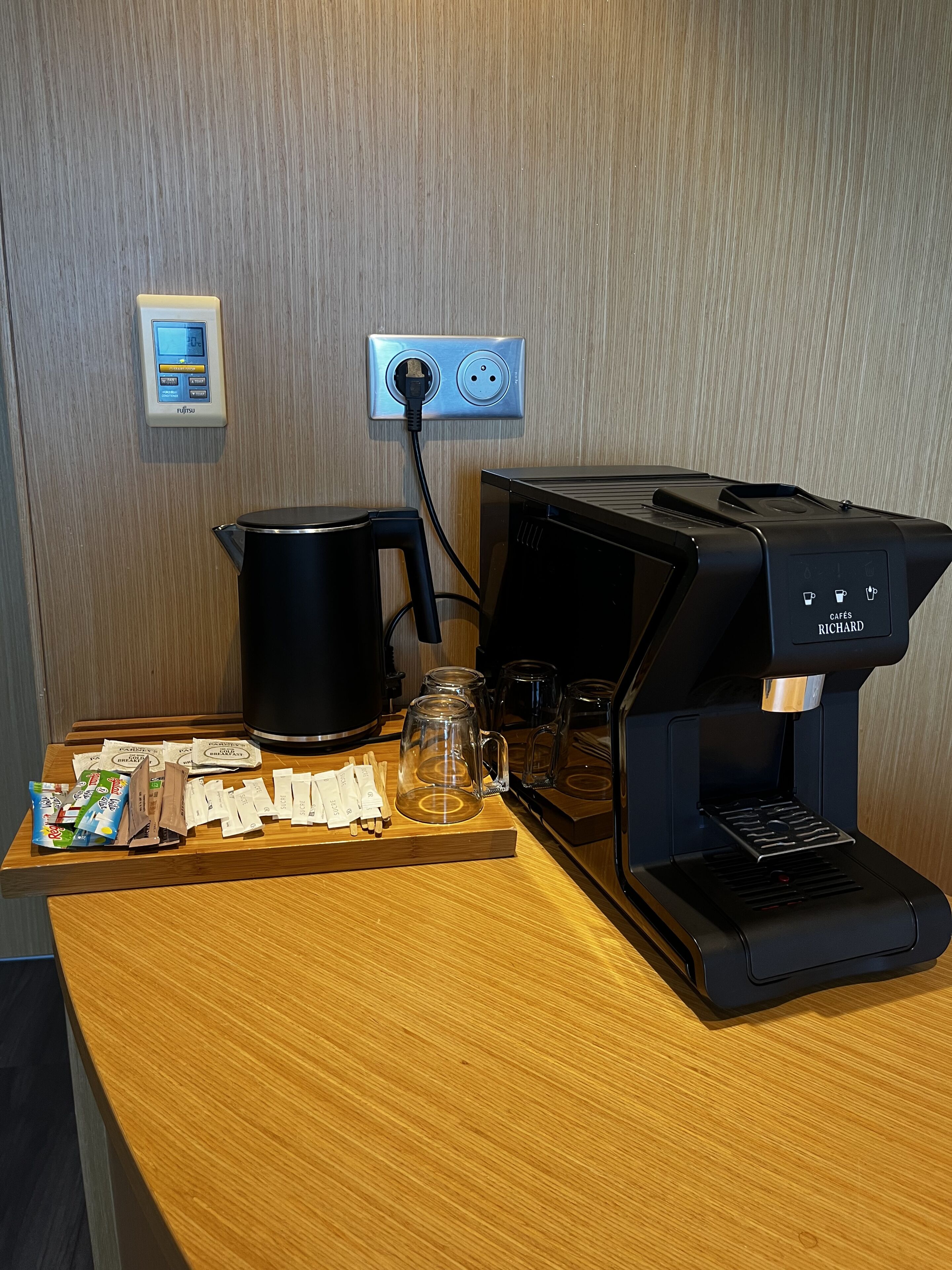 A coffee machine, a kettle, and a power strip on a wooden table.
