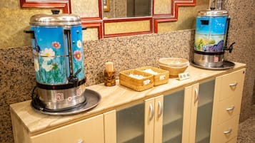Una encimera de cocina con dos cafeteras, una cesta de pan y un armario de madera.