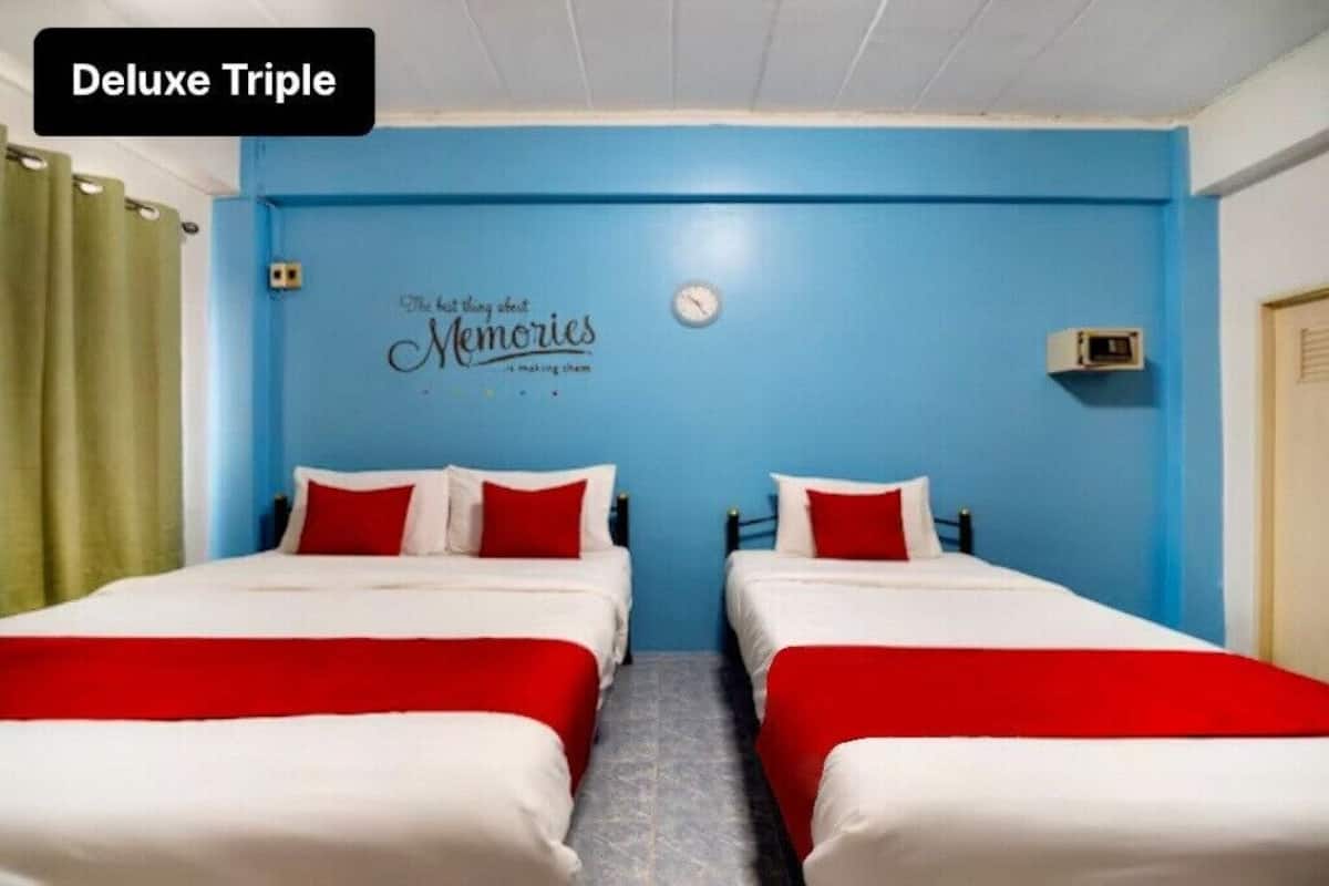 A room with two beds, each with red and white bedding, and a blue wall with a clock and a sign that says "The best things about Memories are making them."