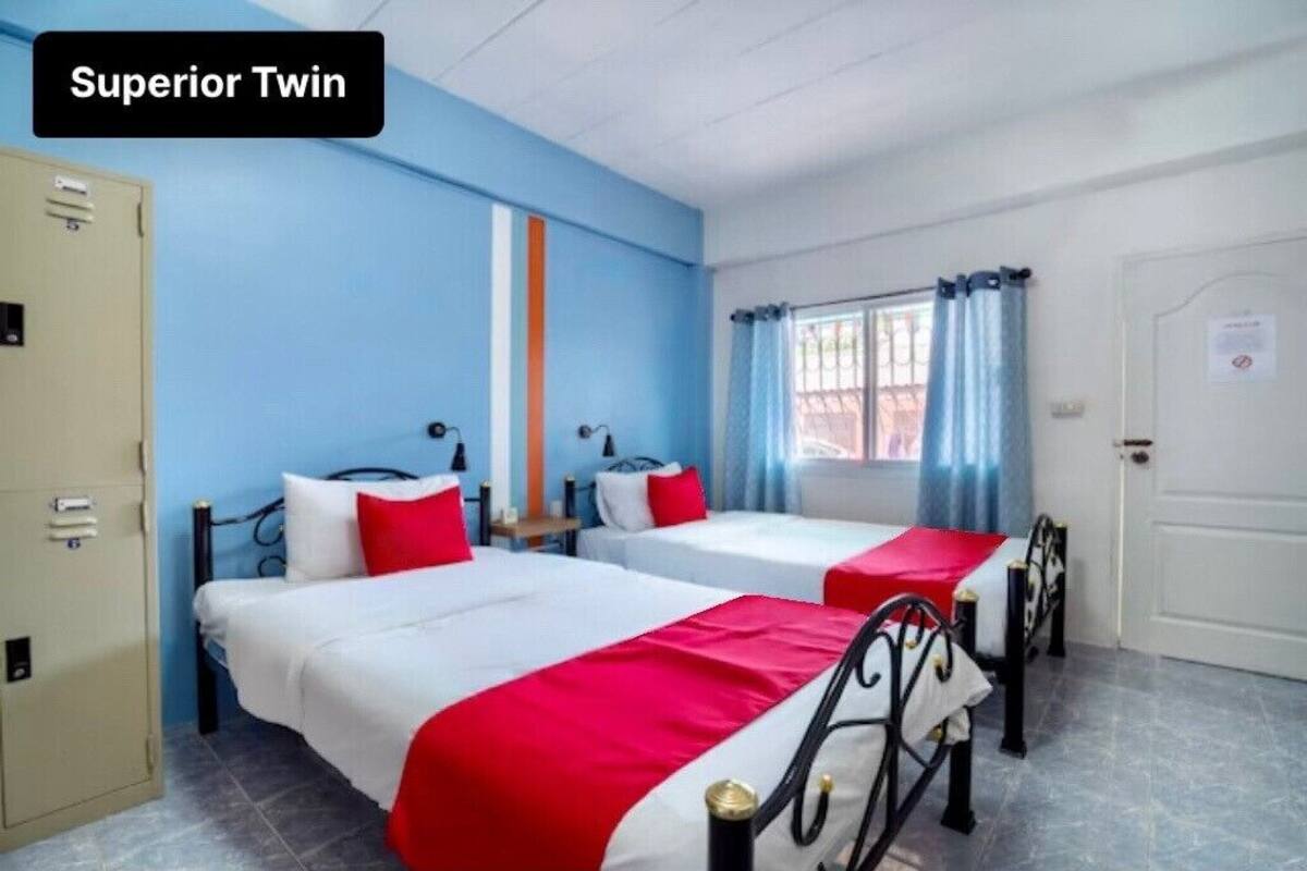 A hotel room with two beds, a wardrobe, and a window with curtains.