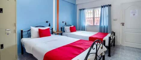 Quarto de hotel com duas camas, um guarda-roupa e uma janela com cortinas.