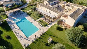 Vista aérea de una propiedad con piscina, mobiliario exterior y jardín ajardinado.