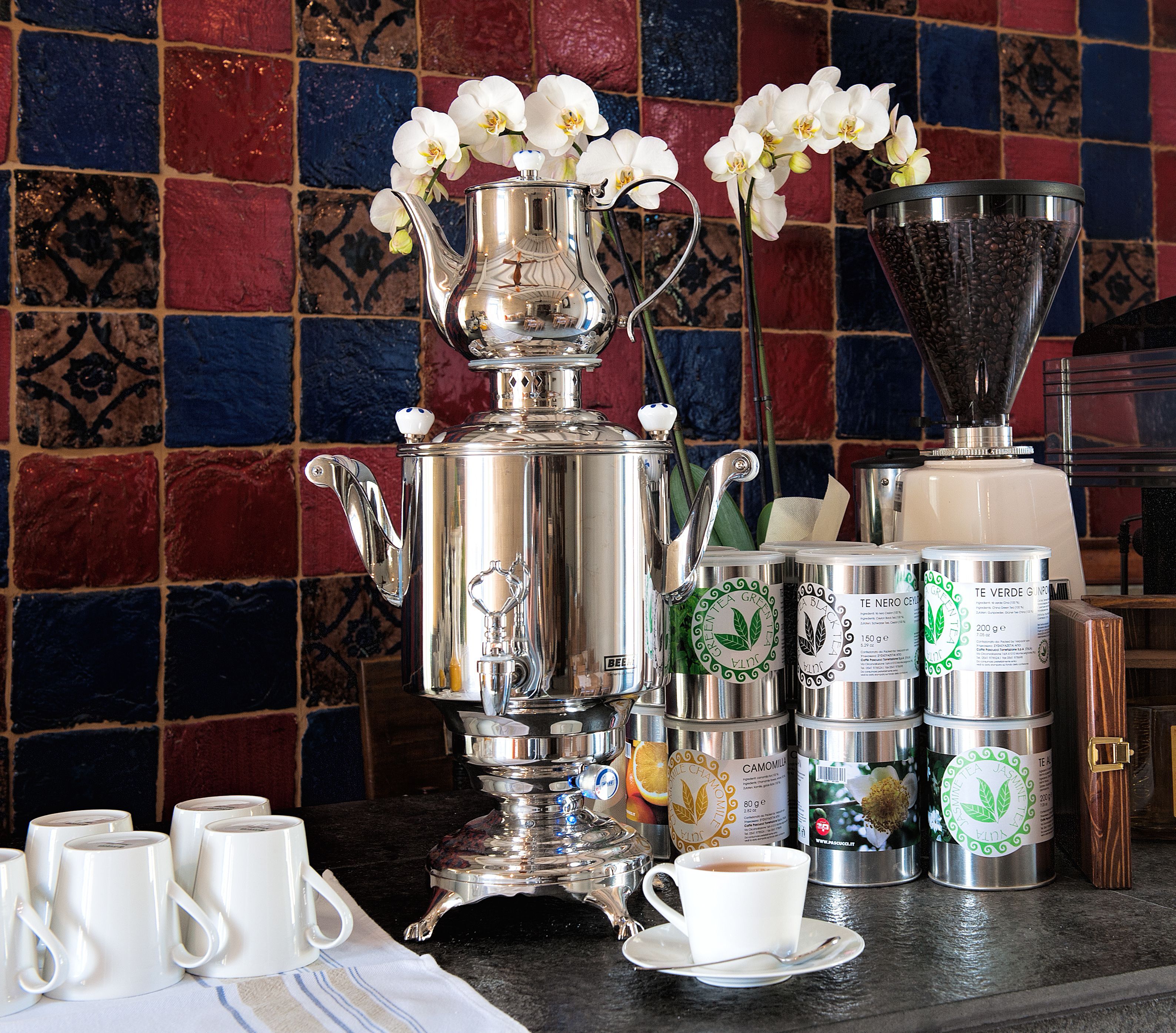 Een koffiehoek met een zilveren espressomachine, koffiekopjes en een molen.