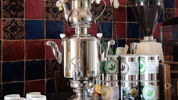 A coffee station with a silver espresso machine, coffee cups, and a grinder.