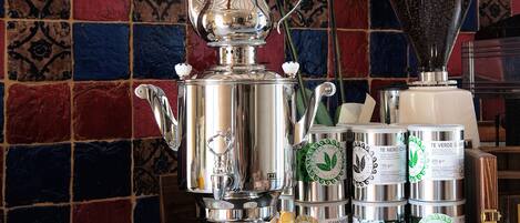 A coffee station with a silver espresso machine, coffee cups, and a grinder.