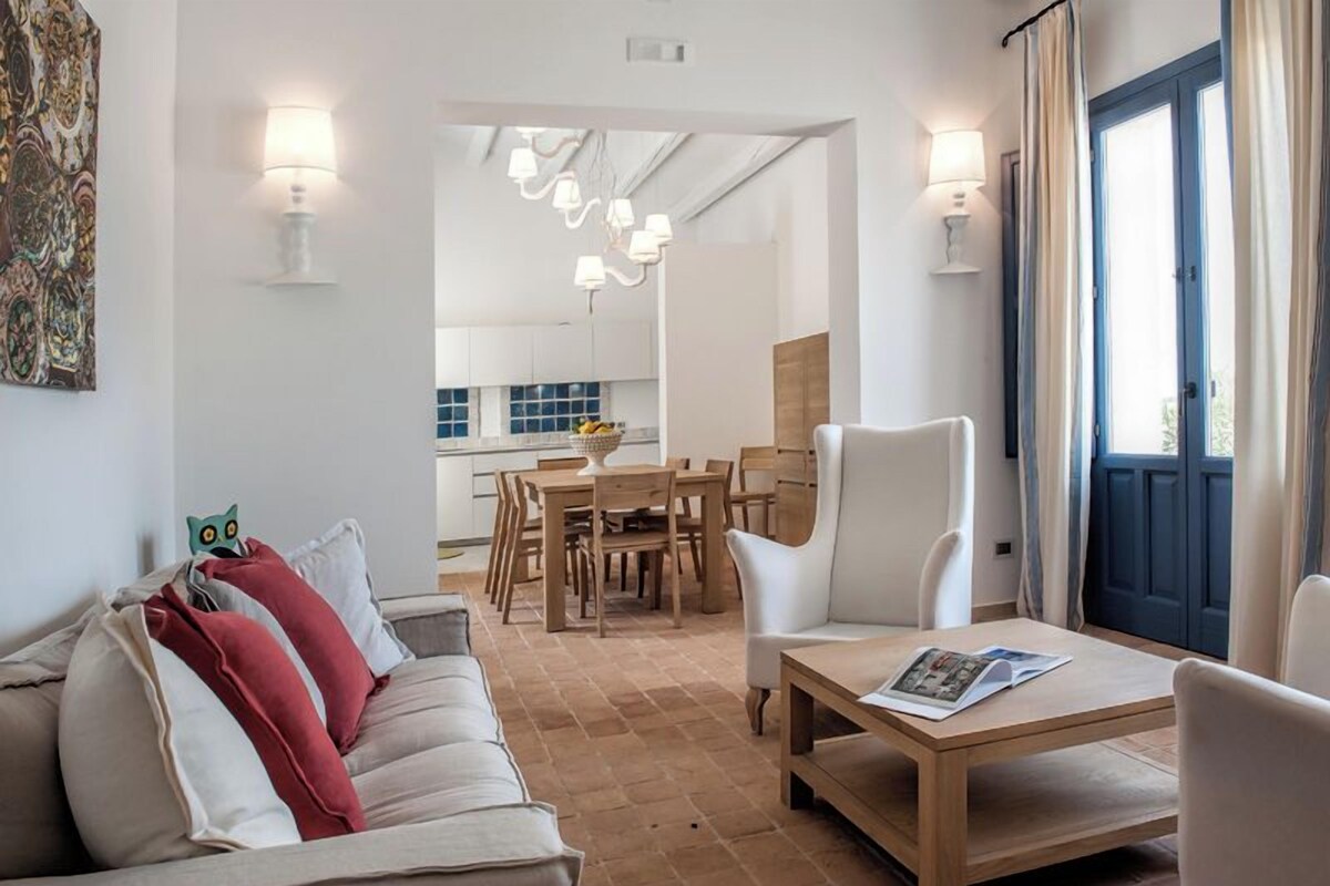 Una sala moderna con un sofá, una mesa de comedor y una cocina al fondo.
