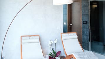 Relax in a stylish room with a comfortable lounge area, featuring two plush chairs, a floor lamp, and a glass door leading to another space.