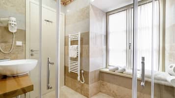 Un baño con cabina de ducha de vidrio, un lavamanos blanco y un perchero para toallas.