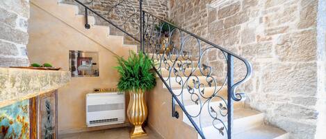 A staircase with stone walls, a metal railing, and a potted plant.
