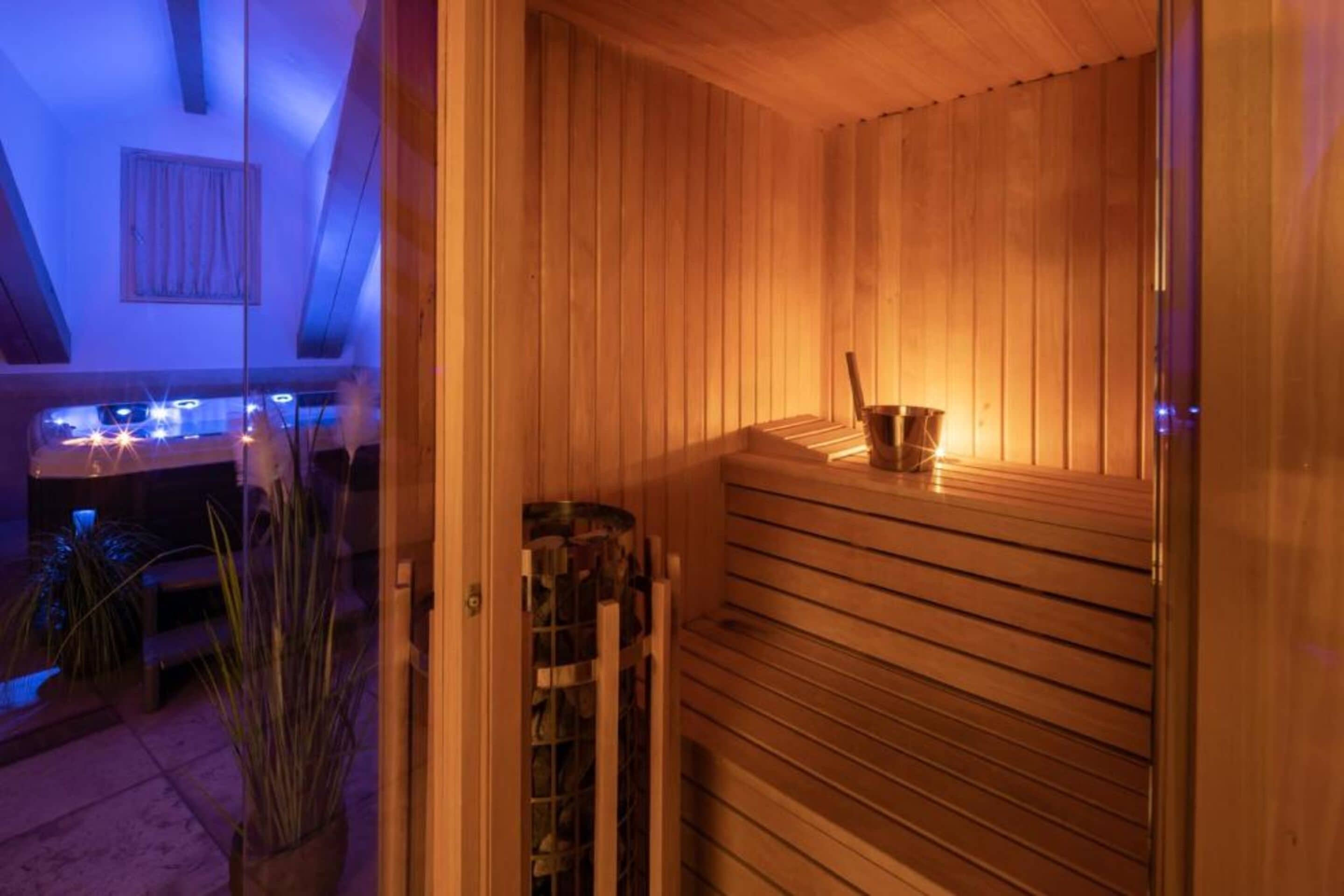 A sauna with wooden slats and a bench, a small table with a candle, and a window with curtains.