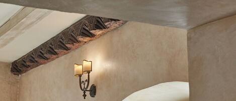 A room with a stone wall, a wooden ceiling, and a wall-mounted light fixture.