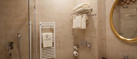 A bathroom with a glass-enclosed shower, a white toilet, a sink with a mirror, and a towel rack with multiple towels.