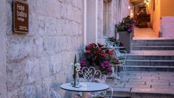 Un hôtel appelé « Hotel Bastina Heritage », doté d’une terrasse et illuminé de guirlandes lumineuses.