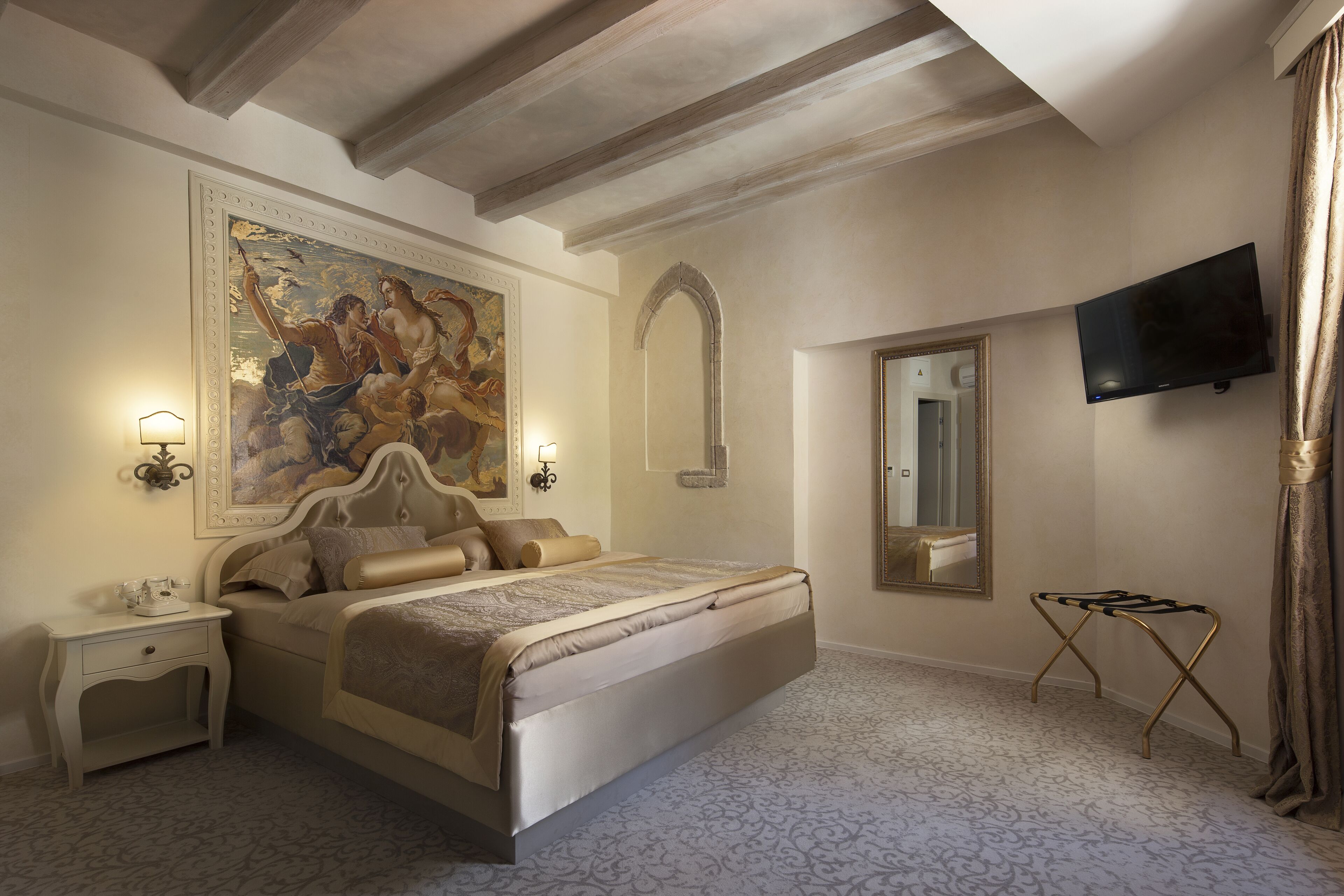 A bedroom with a large bed, a painting, a television, and a mirror.
