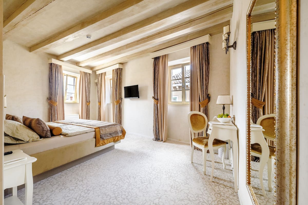 Ein Hotelzimmer mit einem Bett, einem Schreibtisch mit Stuhl, einem Fernseher und einem großen Spiegel.