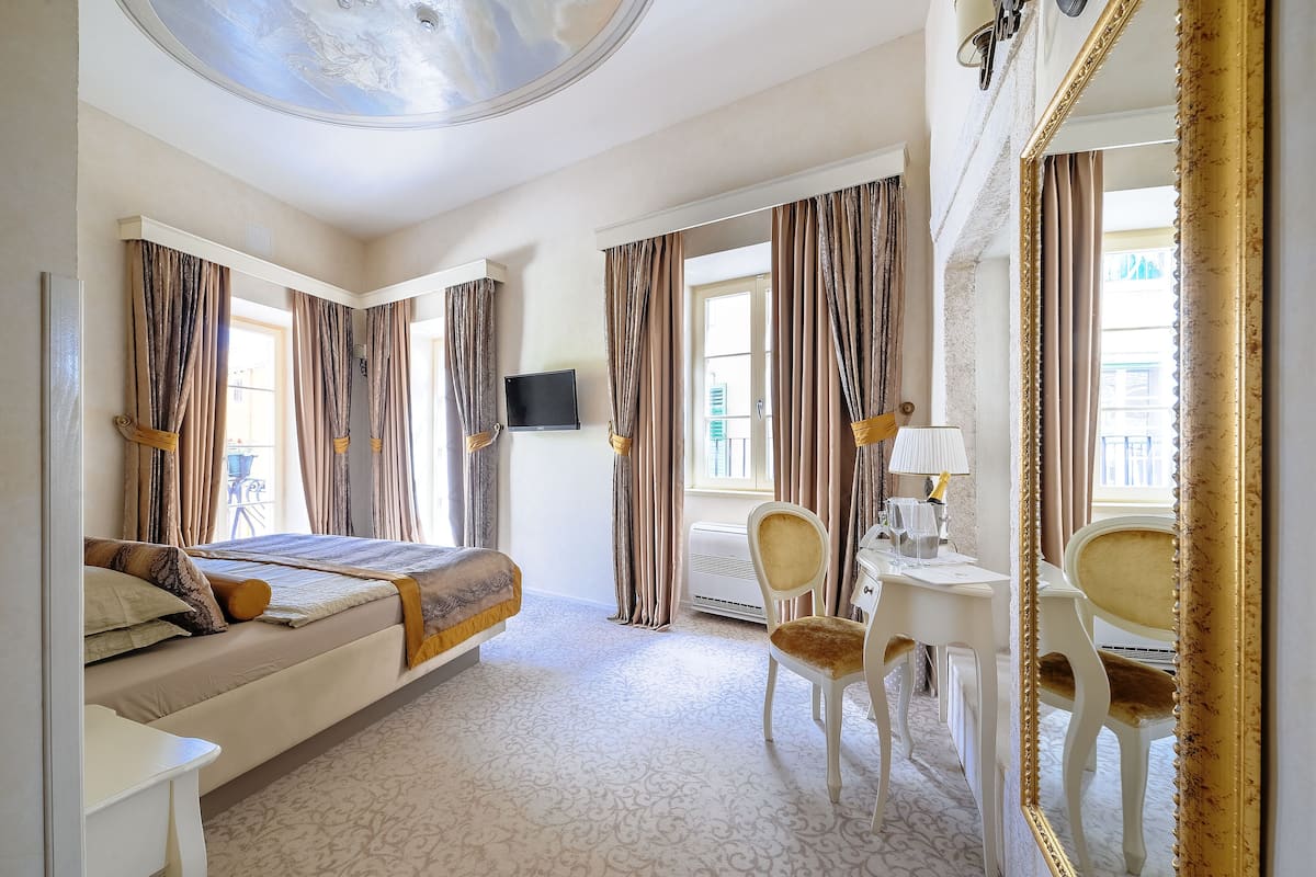 Ein Hotelzimmer mit einem Bett, einem Schreibtisch mit Stuhl, einem Fernseher und einem großen Spiegel.
