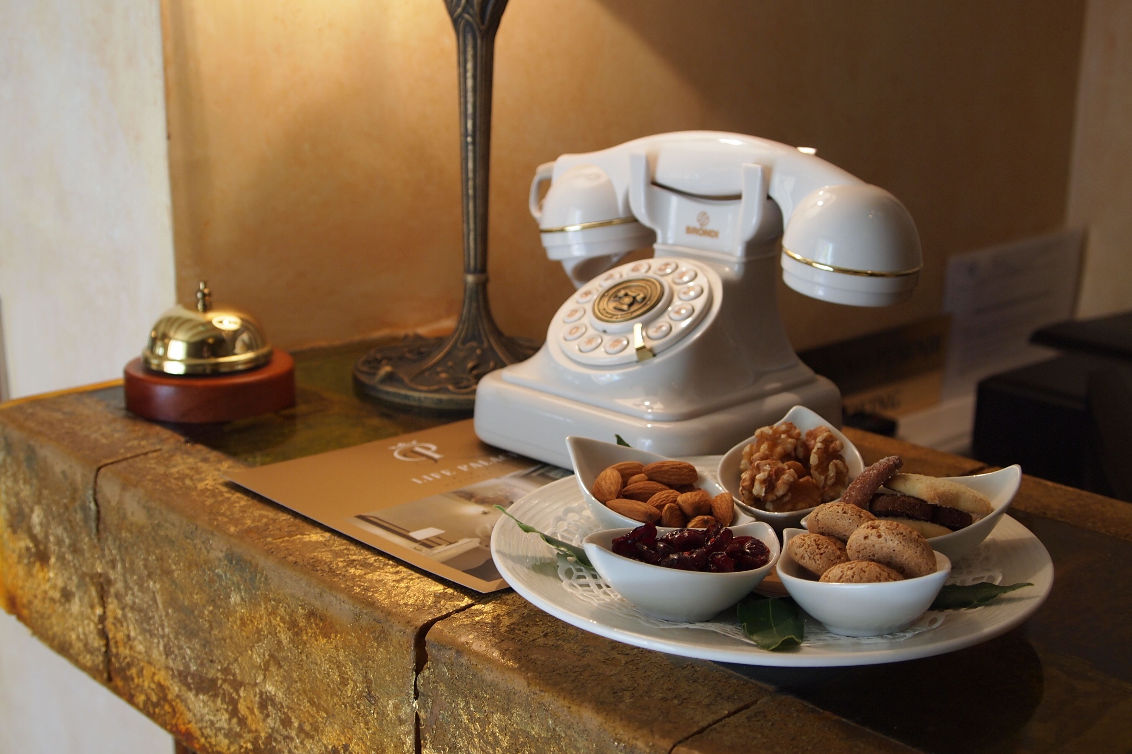 A vintage rotary phone on a wooden counter with a plate of nuts and dried fruits.