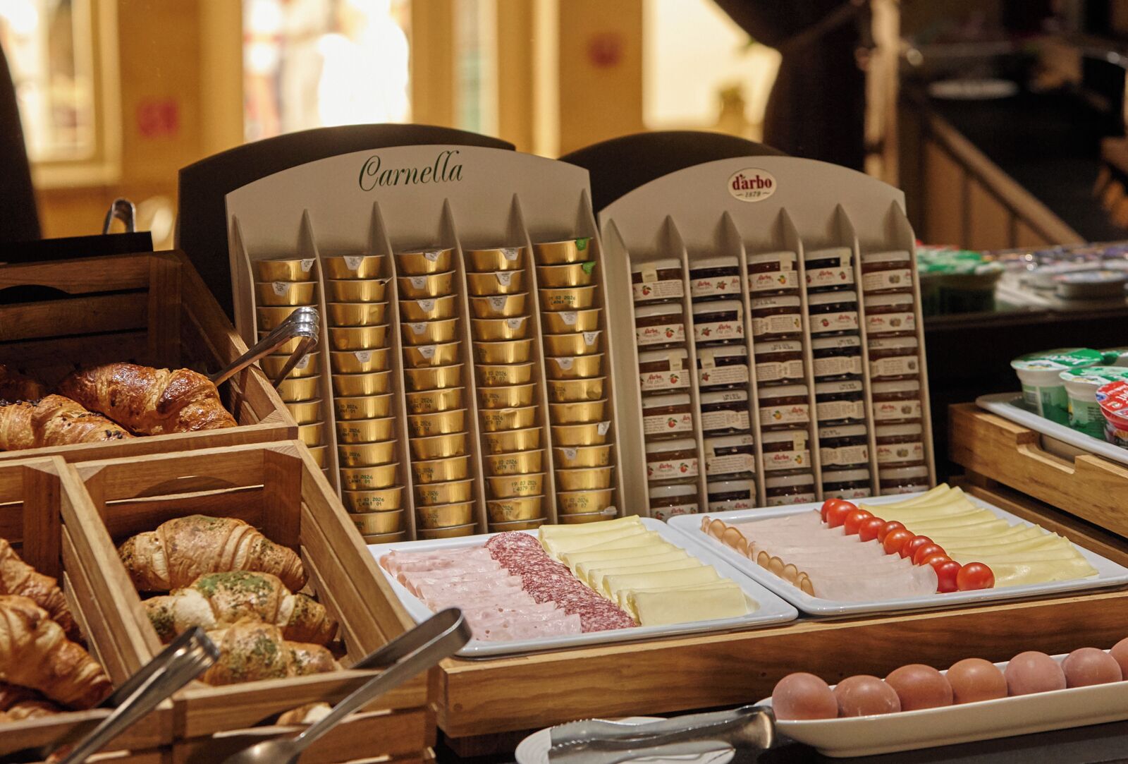 A display of various food items including pastries, cheeses, and cured meats.