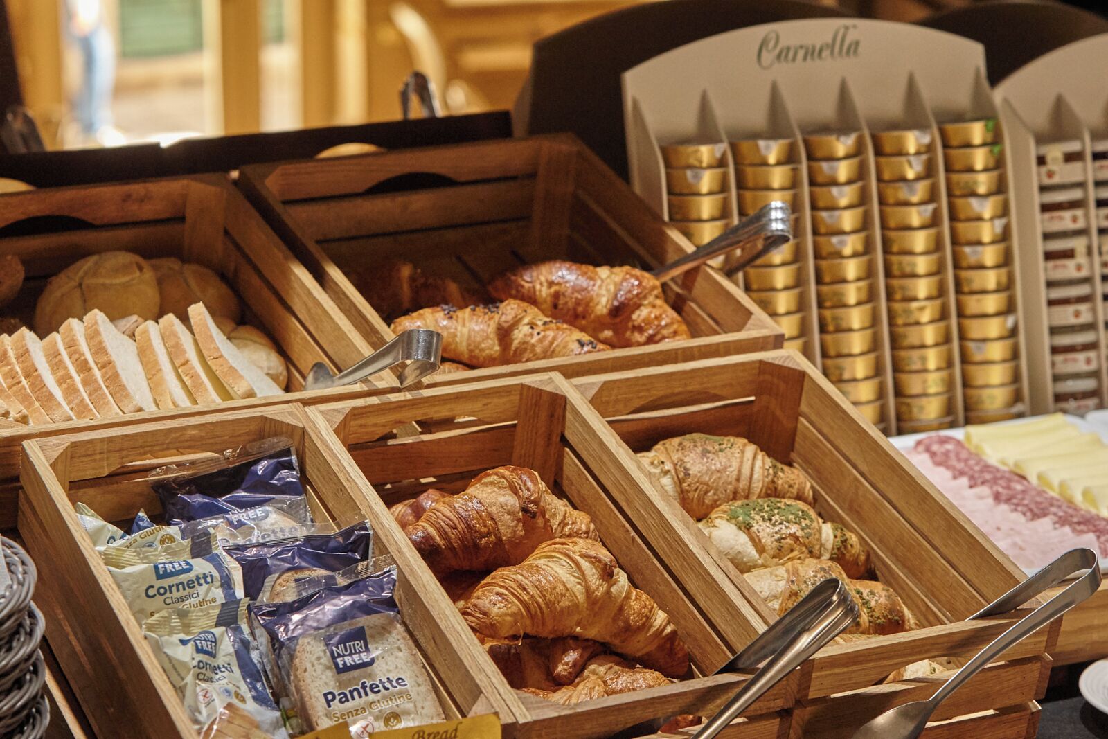 Une vitrine de boulangerie présentant différents types de pains et de viennoiseries, notamment des croissants et des baguettes, disposés dans des caisses en bois.