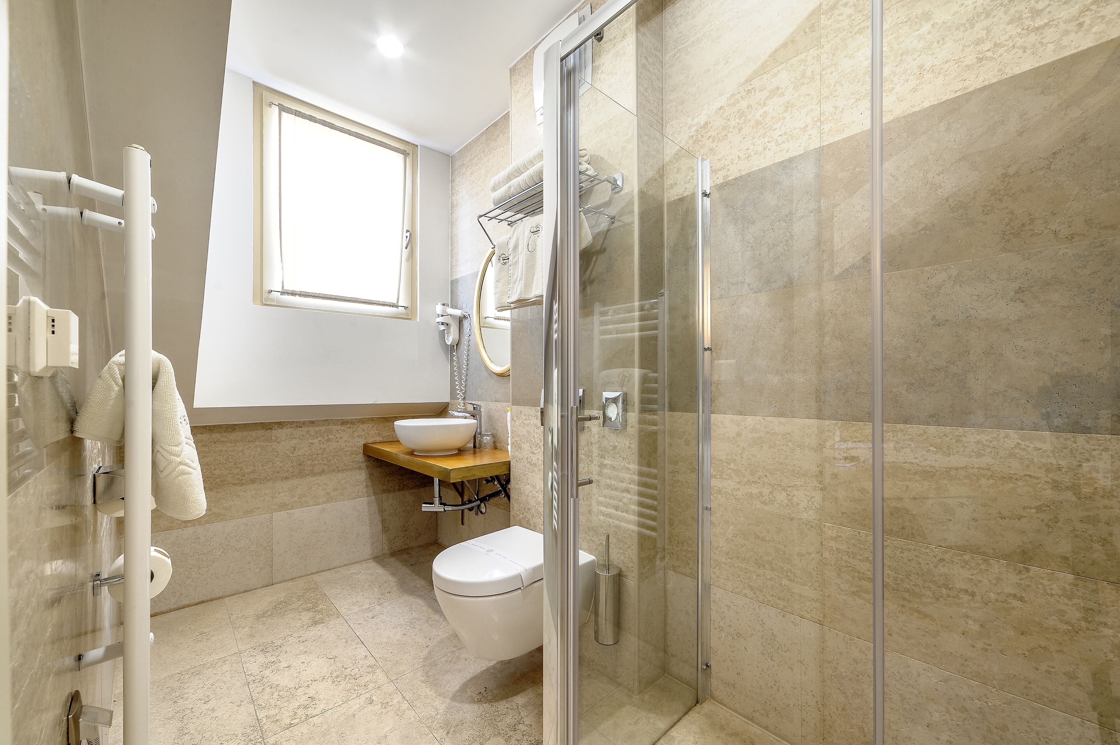 A modern bathroom with a glass-enclosed shower, a white toilet, a sink with a beige countertop, and a towel rack.
