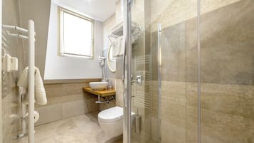 A modern bathroom with a glass-enclosed shower, a white toilet, a sink with a beige countertop, and a towel rack.