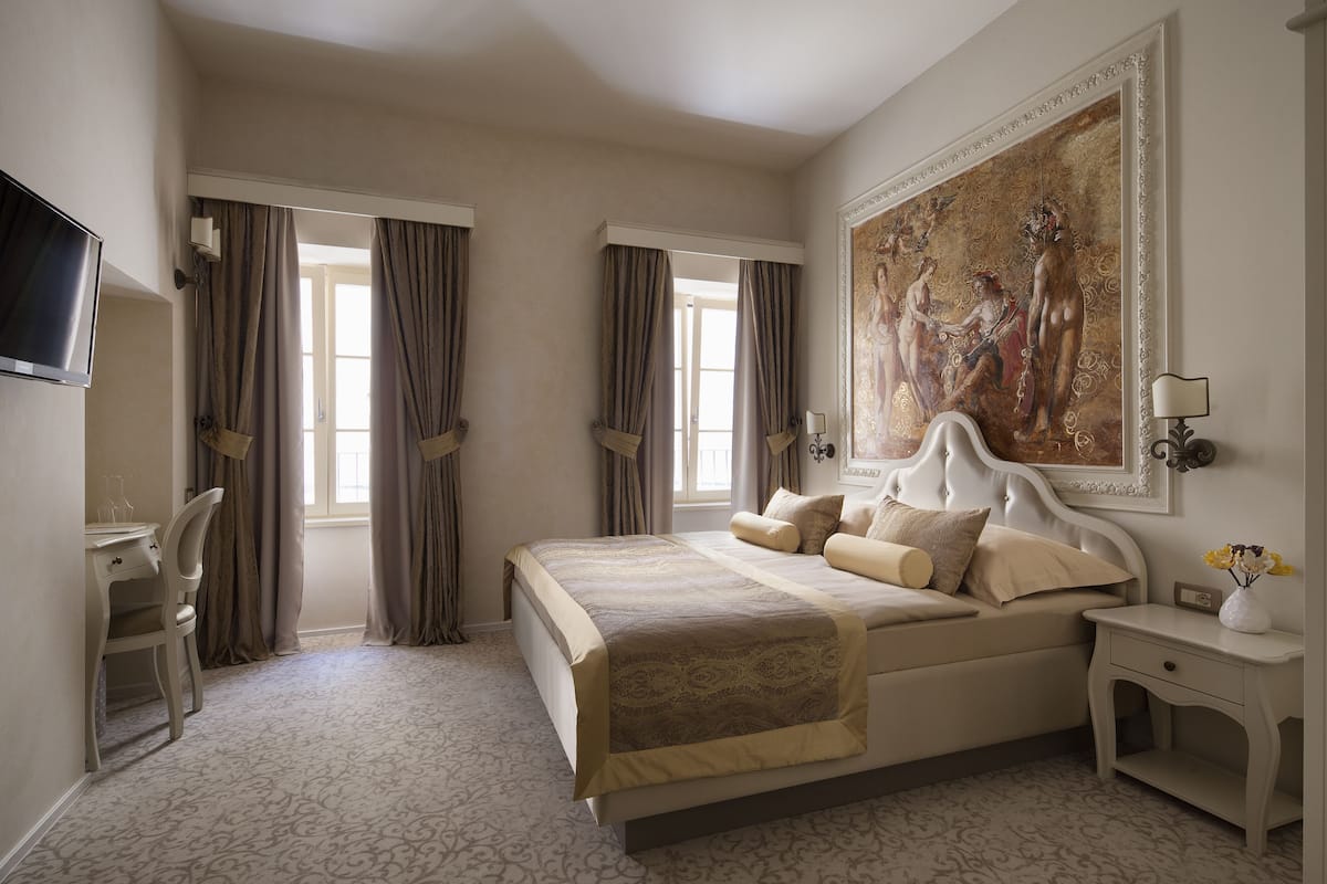 Ein Hotelzimmer mit Bett, Schreibtisch, Stuhl, Fernseher und einem Bild an der Wand.