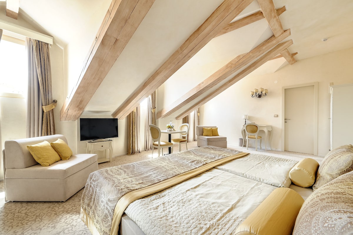 Ein Schlafzimmer mit einem großen Bett, einem Sofa, einem Fernseher und einem Schreibtisch mit Stühlen.