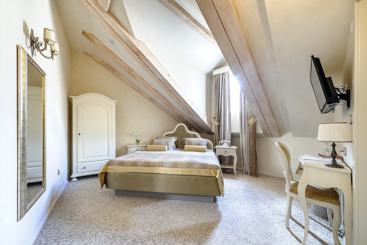 Ein Schlafzimmer mit einem großen Bett, einem Schreibtisch, einem Stuhl, einem Kleiderschrank und einem Spiegel.