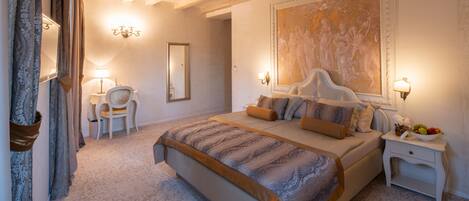 A bedroom with a large bed, a chair, a nightstand, and a painting on the wall.