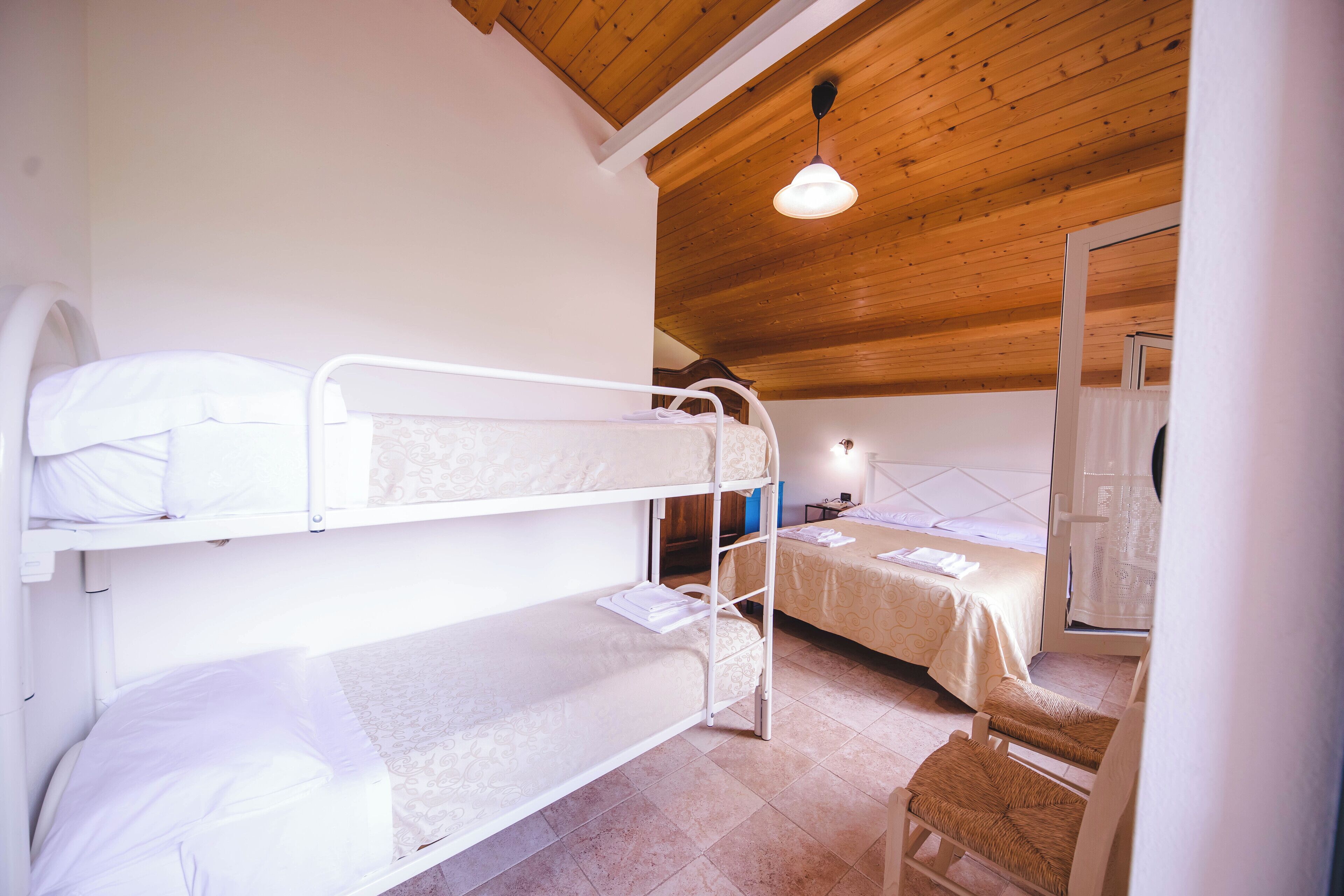 A room with bunk beds, a small table, and a chair.