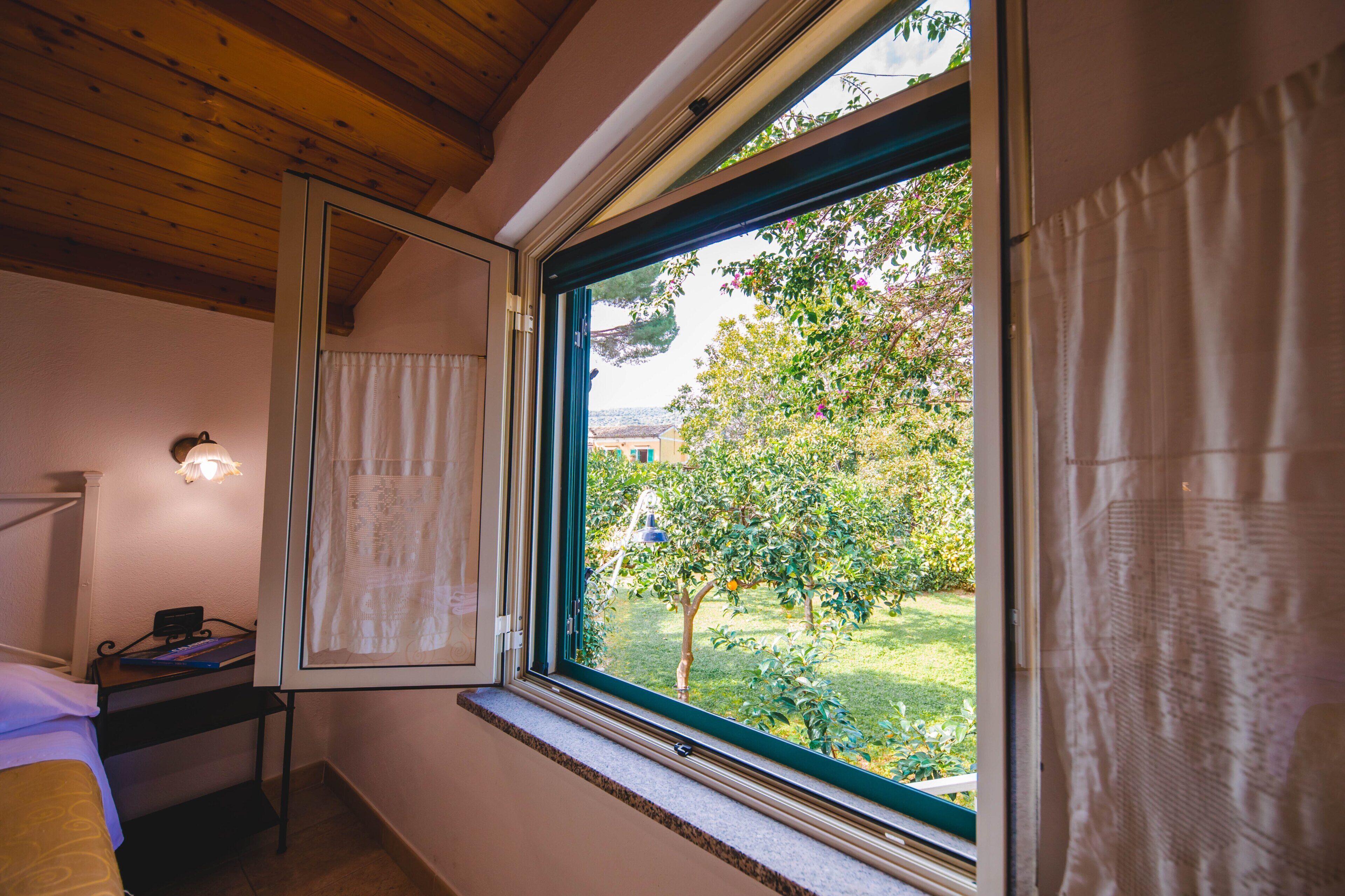 A bedroom with a window, a bedside table, and a lamp.