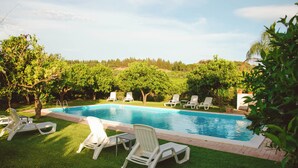 A swimming pool with white lounge chairs and a grassy area.